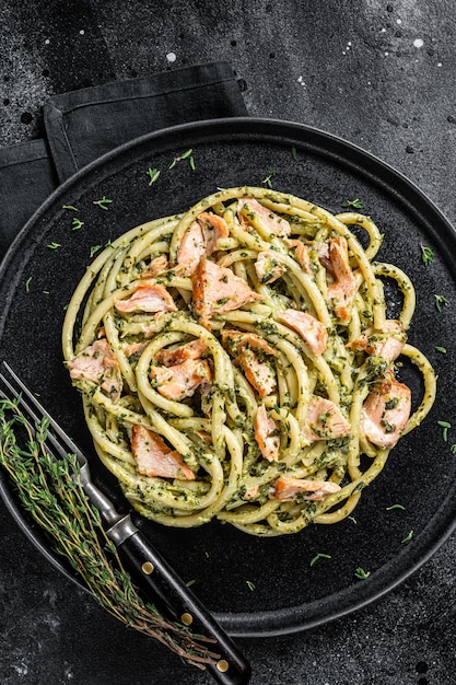 Bucatini con filetto di salmone affumicato e spinaci cremosi sfondo nero vista dall'alto