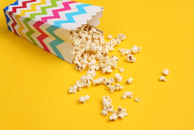 Bucket box with delicious salted popcorn on a yellow background Fast food and movie snack