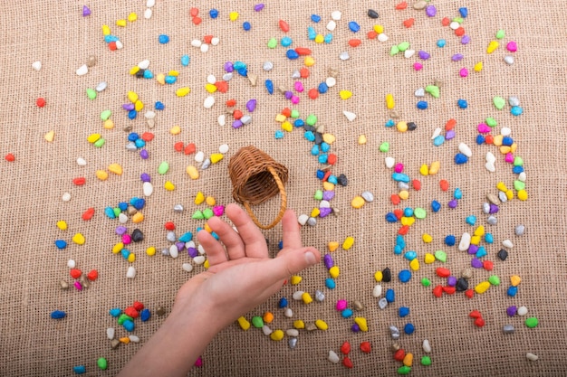 Bucket of colorful pebbles spill on canvas background