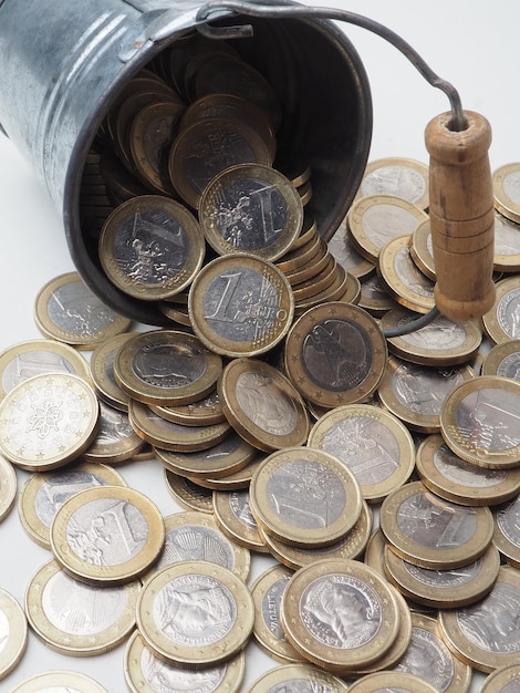 A bucket of euro coins is on a table.