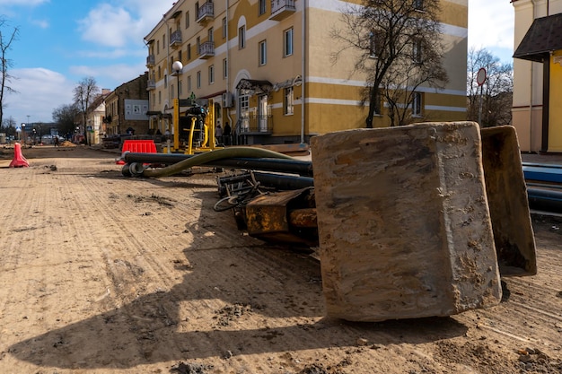The bucket from the excavator lies on the construction site\
repair of asphalt on the roadway in the city removal of the old\
asphalt concrete pavement