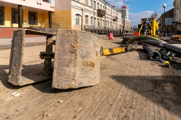 The bucket from the excavator lies on the construction site\
repair of asphalt on the roadway in the city removal of the old\
asphalt concrete pavement