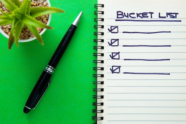 Photo bucket list on notebook with a pen