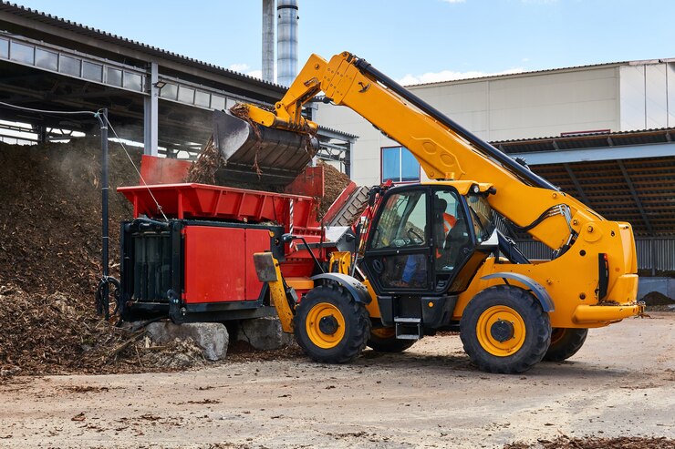 Bucket loader loads wood bark into an industrial tree chipper in a woodworking industry