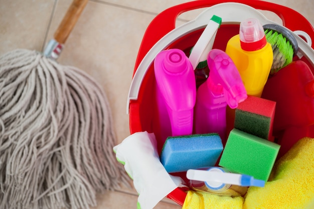 Bucket with cleaning supplies and mop on tile floor