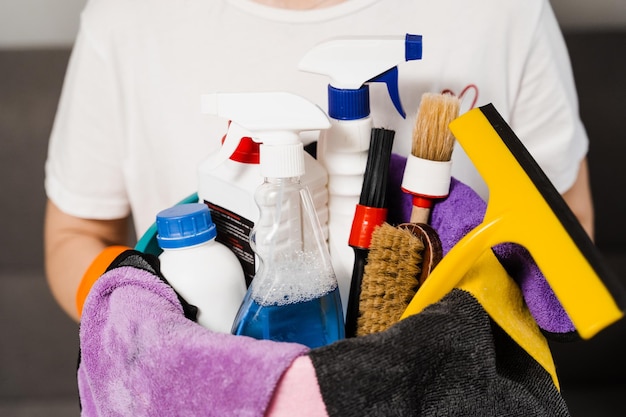 Bucket with detergent and microfiber rags for house cleaning in hands of cleaner Professional domestic cleaning service