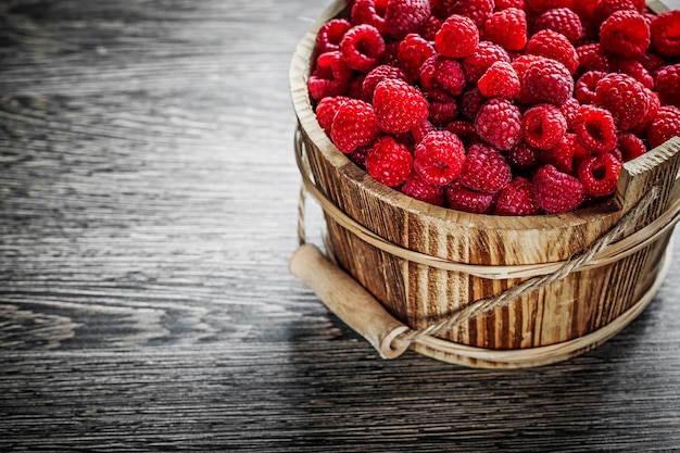 Bucket with juicy raspberries on wooden board