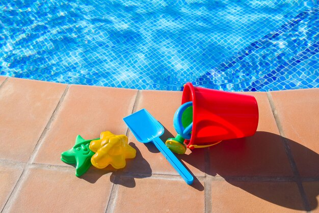 Bucket with plastic beach toys near pool