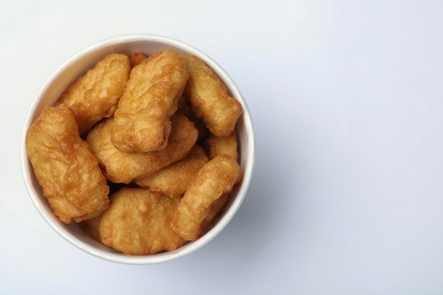 Bucket with tasty chicken nuggets on white background top view