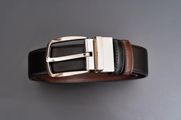 Photo buckle doublesided black and brown leather belt with an unbuttoned buckle on a black background