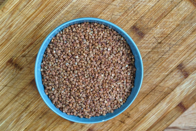 Buckwheat in a bowl on wooden background top view