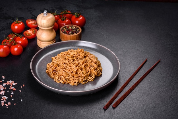 Buckwheat flour noodles with sauce sesame herbs and spices on a dark concrete background