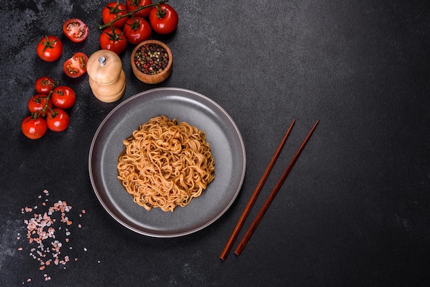 Buckwheat flour noodles with sauce sesame herbs and spices on a dark concrete background