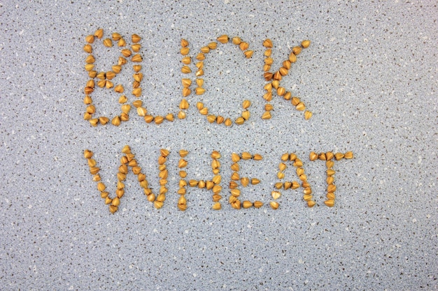 Buckwheat grain The word buckwheat from grains of buckwheat on a blue background Authentic buckwheat folded into the word BUCKWHEAT font