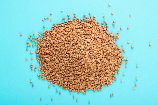 Buckwheat heap on blue background Raw buckwheat on blue