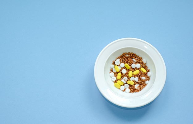 Фото Гречка в белой тарелке, смешанная с таблетками