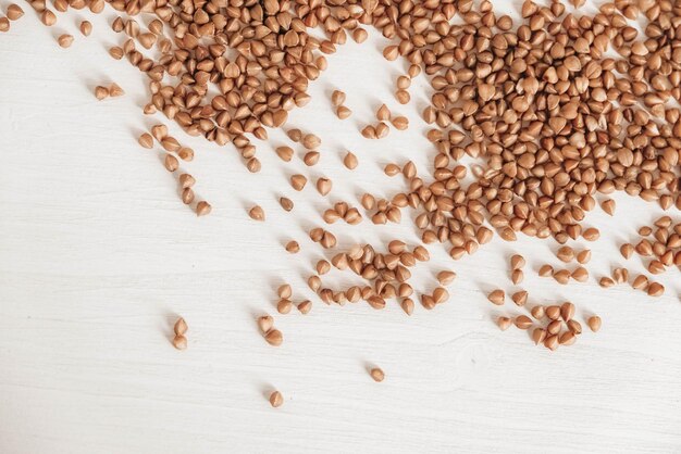 Il grano saraceno è sparso casualmente su uno sfondo bianco. vista dall'alto. copia, spazio vuoto per il testo