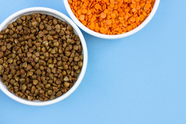 Buckwheat and lentils in plates, top view.