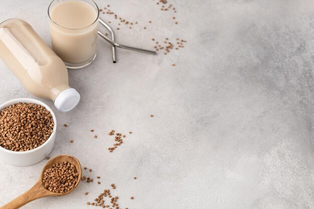 Buckwheat milk in a bottle and a glass cup with an ingredient on a light background