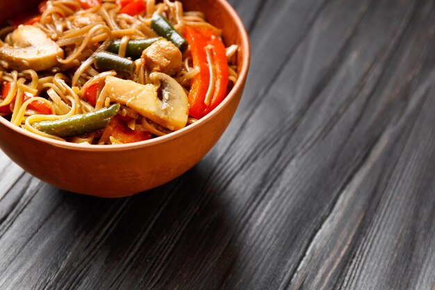 Buckwheat noodles with vegetables and chicken meat on a dark background copy space