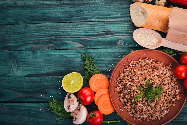 Buckwheat on a plate with fresh vegetables On a wooden background Top view Copy space