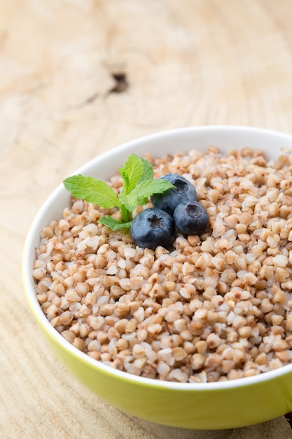 Buckwheat porridge in a bowl with mint leaves and blueberries.