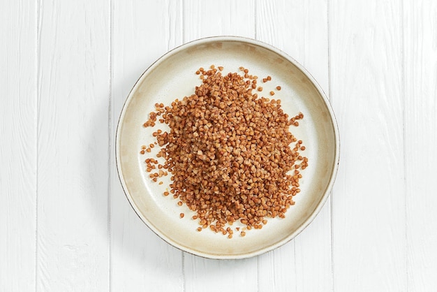 Buckwheat porridge in a plate on a white wooden background