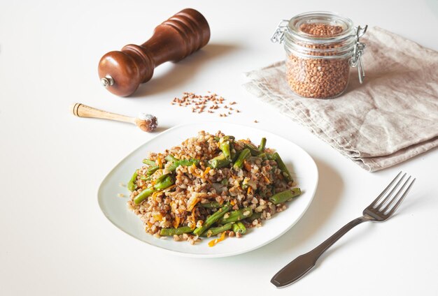 Buckwheat porridge with green beans and carrots buckwheat in a glass jar on a beige napkin