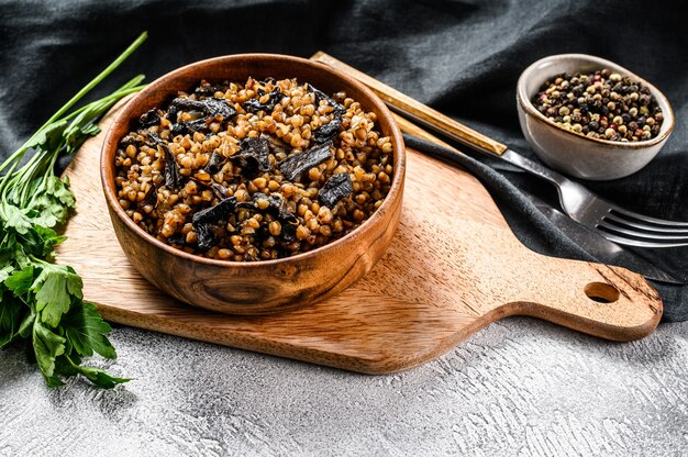 Buckwheat porridge with mushrooms in a wooden pot. . Top view