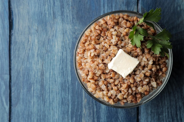 Buckwheat. Porridge with a piece of butter in a glass plate on a blue wooden table. breakfast, healthy food. top view