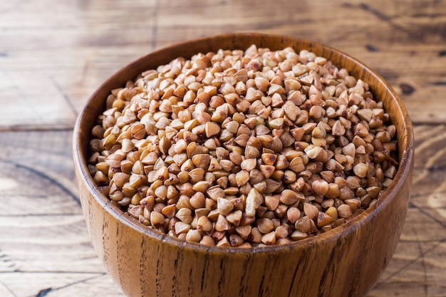 Buckwheat raw in a wooden bowl on a rustic wooden table.