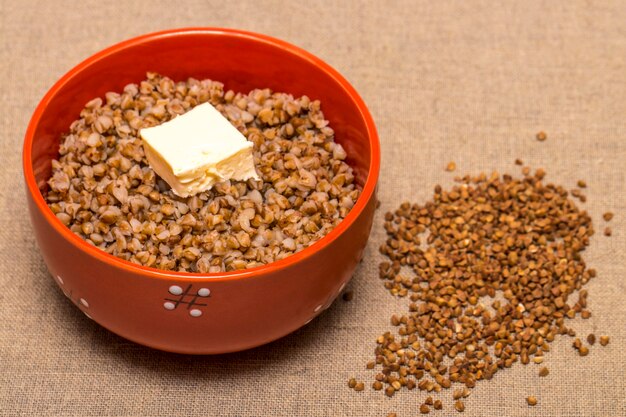 Buckwheat in a red bowl. Healthy food. Buckwheat porridge and butter.