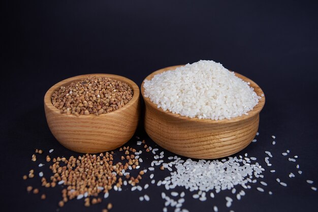 Buckwheat and rice raw in a stylish wooden bowl on a dark surface
