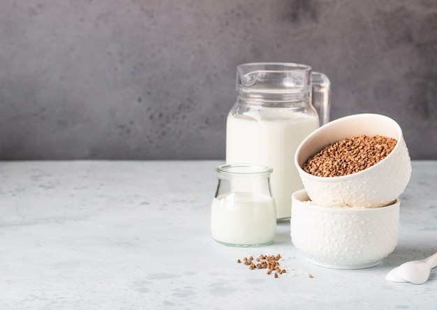 Grano saraceno e riso in ciotole bianche e brocca di latte. colazione salutare.