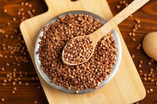 Buckwheat in spoon above bowl on table