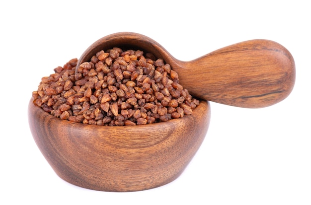 Buckwheat tea in wooden bowl and spoon isolated on white background whole roasted buckwheat grains