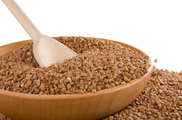 Buckwheat and wood spoon isolated in plate on white surface