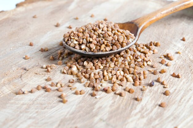 Buckwheat in a wooden spoon on a vintage wooden background