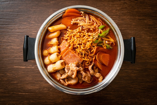 Budae Jjigae или Budaejjigae (армейское тушеное мясо или армейское базовое тушеное мясо). Он полон кимчи, спама, сосисок, лапши рамен и многого другого - популярного корейского стиля еды в горячем горшке.