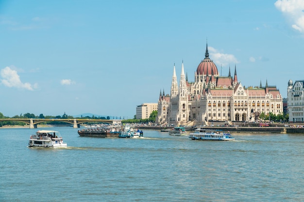 BUDAPEST HUNGARY MAY 112018 Travel boats sailing the Danube river passing by the Hungarian Parliament standing on Pest bank of Danube in Budapest Hungary