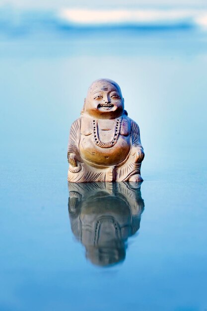 Buddabeeldje op het strand Blauwe golven op de achtergrond