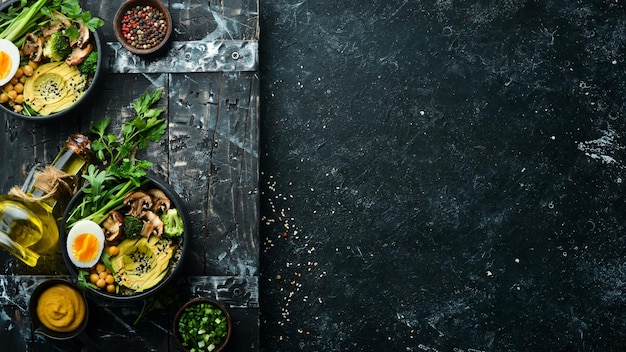 Buddha bowl avocado kikkererwten champignons ei en rucola in een zwarte kom bovenaanzicht vrije ruimte voor tekst