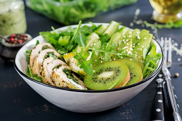 Buddha bowl dish with chicken fillet, avocado, cucumber, fresh arugula salad and sesame. Detox and healthy keto diet bowl concept. Overhead