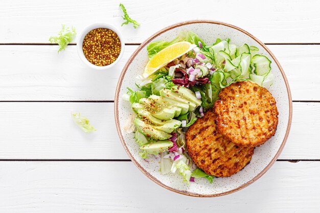 buddha bowl dish with grilled chicken burgers cucumbers avocado and fresh lettuce salad for lunch top view