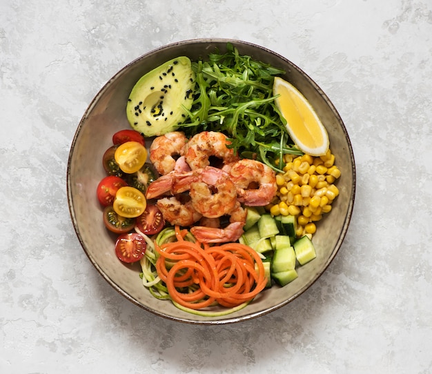 Buddha bowl salade met gegrilde gamba's, rucola, avocado, mais, tomaten en komkommers. ÃƒÂ Ã‚Â¡lean eten, bovenaanzicht. Gezonde lunchschaal. Evenwichtig voedselconcept.