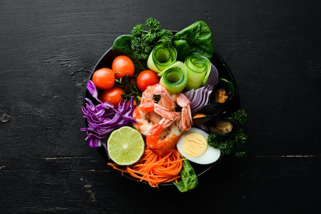 Buddha bowl of seafood Shrimp mussels cabbage cherry tomatoes spinach Seafood dishes Top view Free space for your text