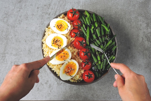 Bulgur, 녹색 콩, 체리 토마토와 삶은 계란 반쪽으로 부처님 그릇. 그릇에 건강에 좋은 음식. 식이 영양의 개념.