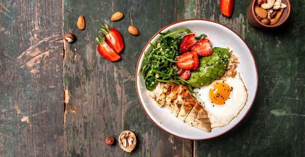 Foto ciotola di buddha con rucola di pollo e fragole keto dieta cibo ricetta sfondo vista dall'alto in formato banner lungo