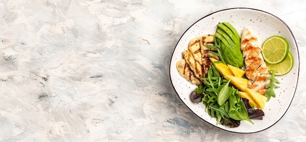 Buddha bowl with pineapple salad, grilled chicken breast, halloumi, avocado and lime