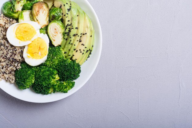 Buddha bowl with quinoa eggs avocado brussels sprouts and broccoli Food vegan salad on wooden backgground